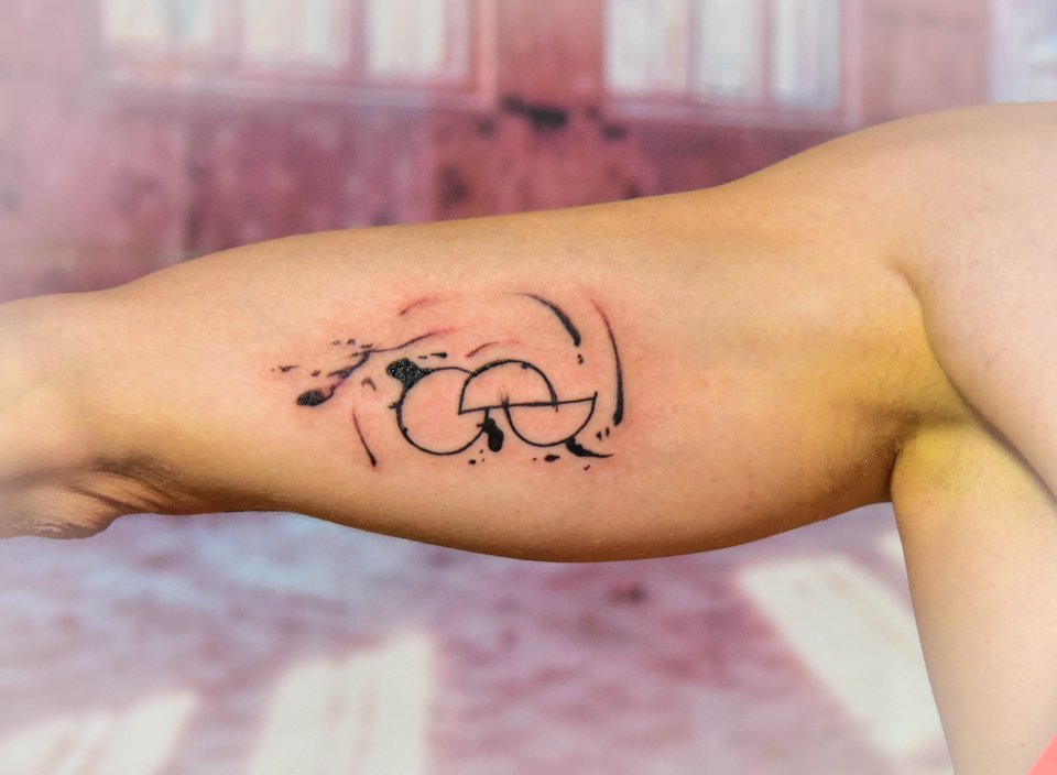 Abstraktes Tattoo aus Linien und Kreisen am Oberarm