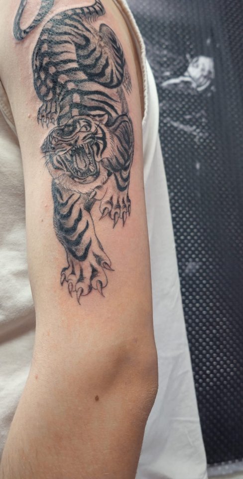 Kletternder Tiger in Schwarz-Grau am Oberarm