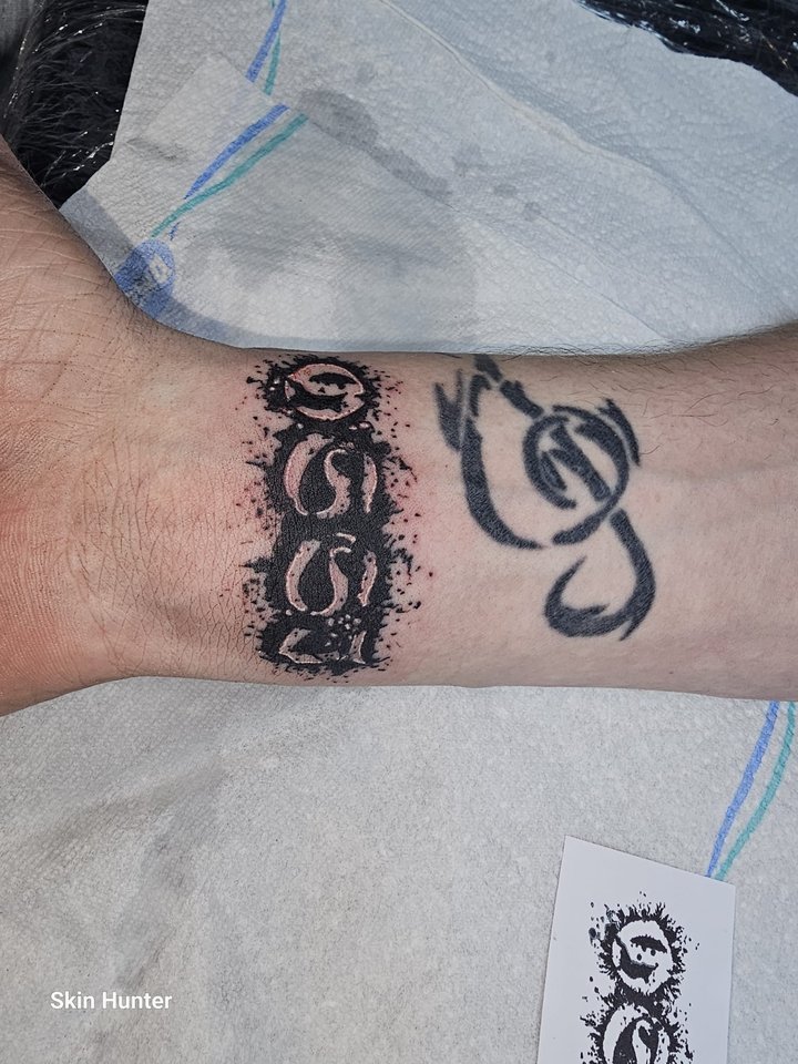 Schwarzes Armband-Tattoo mit Notenschlüssel am Handgelenk