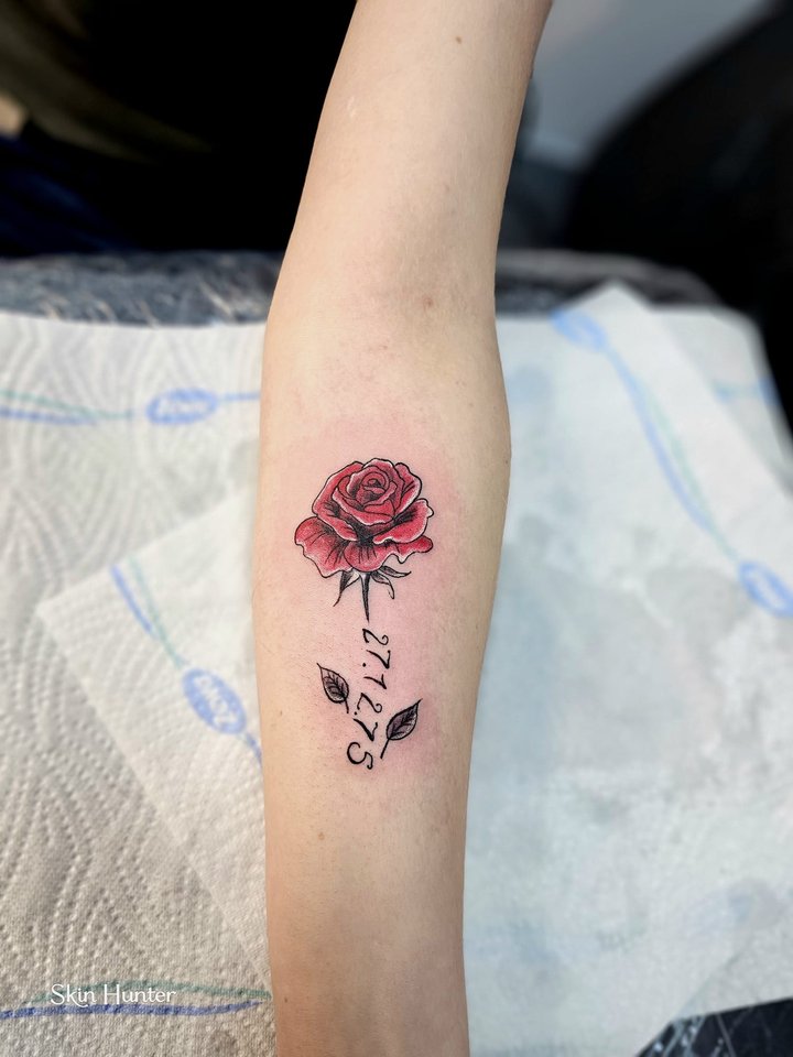Kleine rote Rose mit Datum am Unterarm