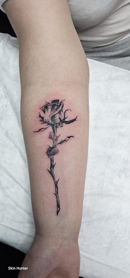 Schwarze Fineline-Rose mit langem Stiel am Unterarm