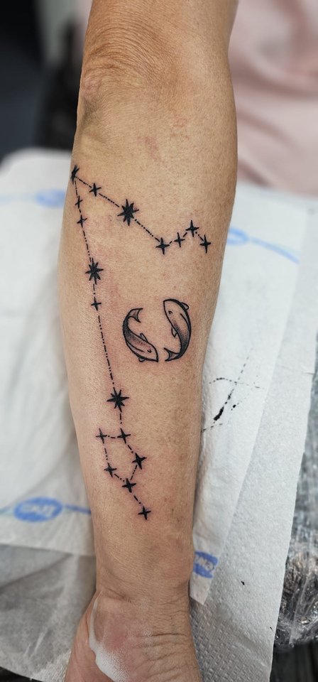 Sternbilder aus feinen Linien und Punkten am Unterarm
