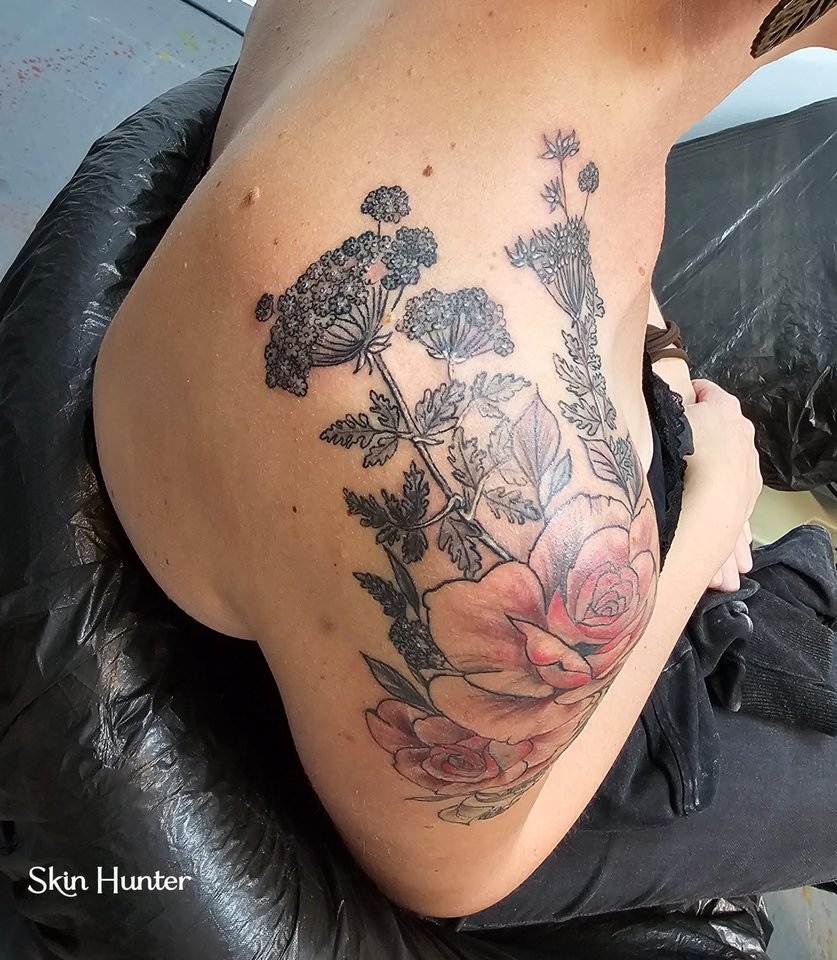 Florales Tattoo mit Blüten und farbiger Rose an der Schulter