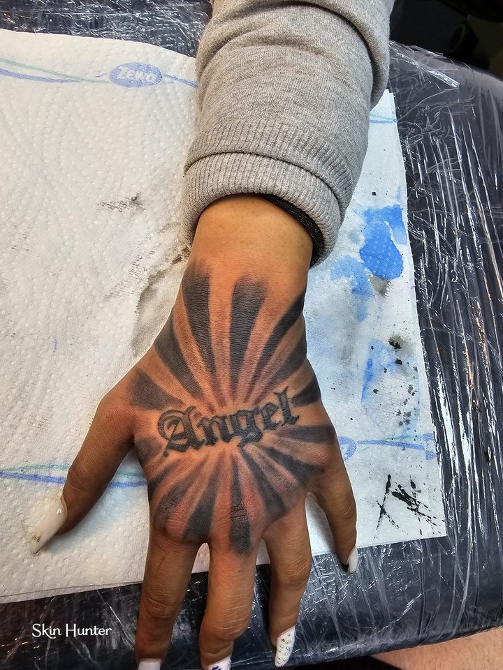 Hand-Tattoo mit Schriftzug Angel und Strahlen in Schwarz-Grau