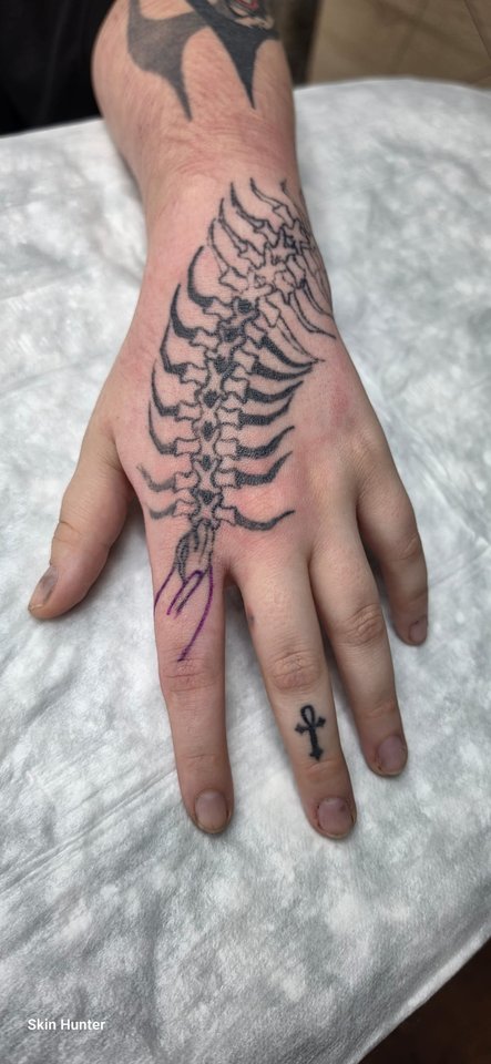 Farnblatt mit kleinem Kreuz auf Hand und Finger