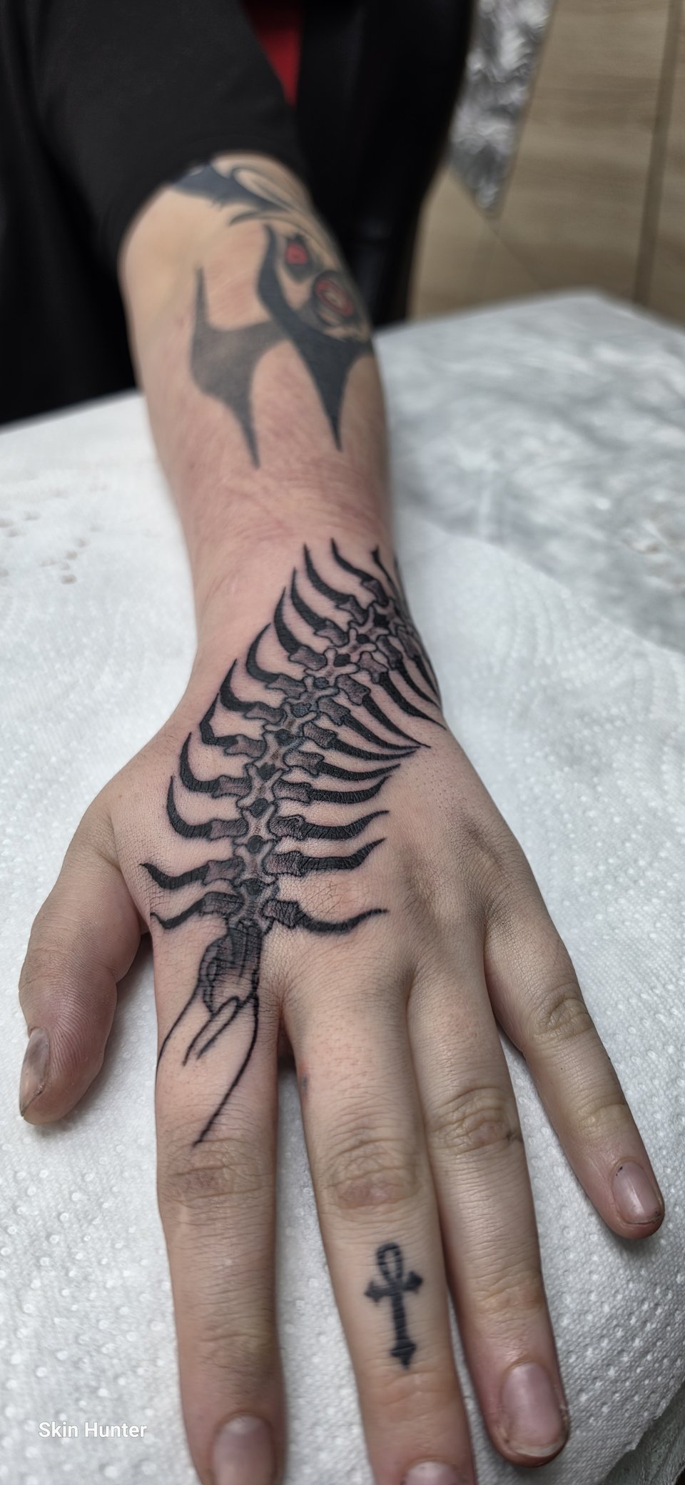Hand-Tattoo eines Tausendfüßlers über Handrücken und Finger