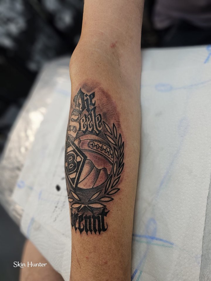 Schriftzug im Chicano-Stil mit Würfel in Schwarz-Grau am Unterarm