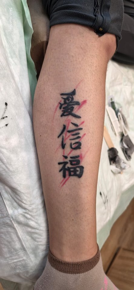 Drei japanische Schriftzeichen mit roten Akzenten an der Wade