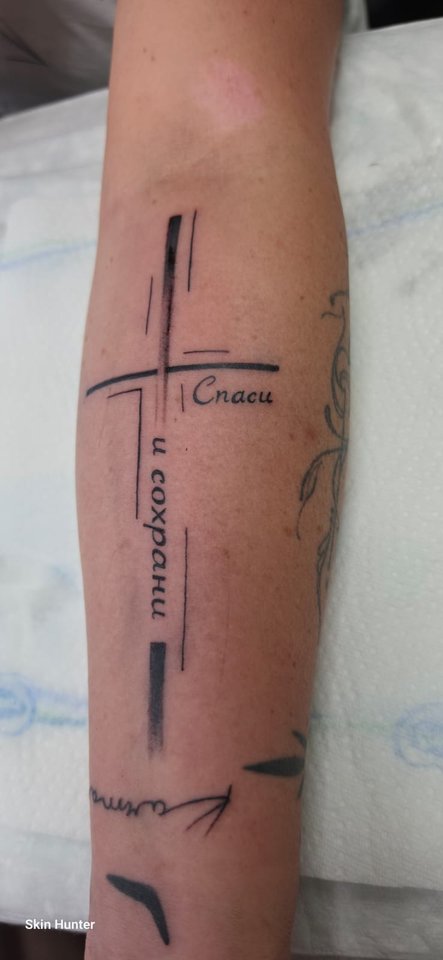 Kreuz aus Linien mit Schriftzügen am Unterarm