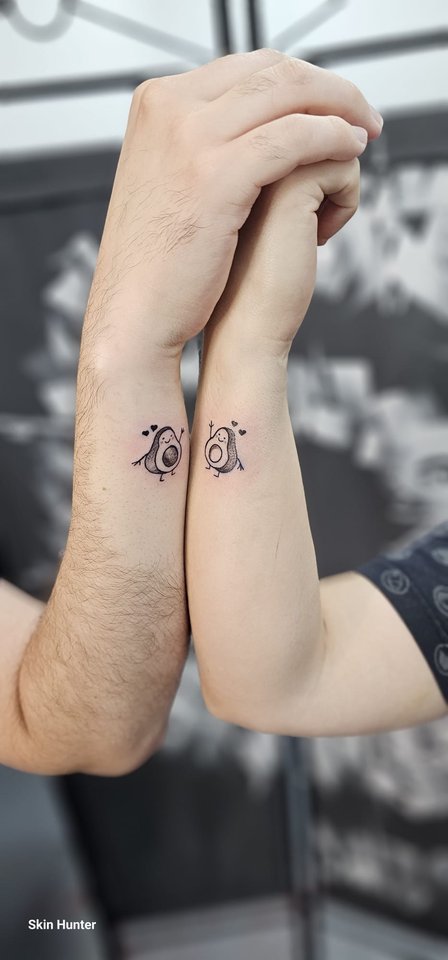 Zwei passende Buchstaben-Tattoos an zwei Unterarmen
