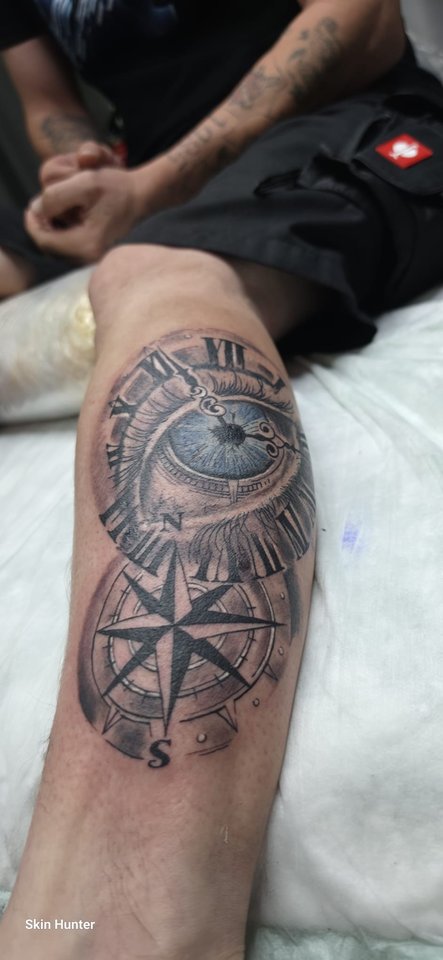 Realistisches Auge mit Uhr und Kompassrose an der Wade