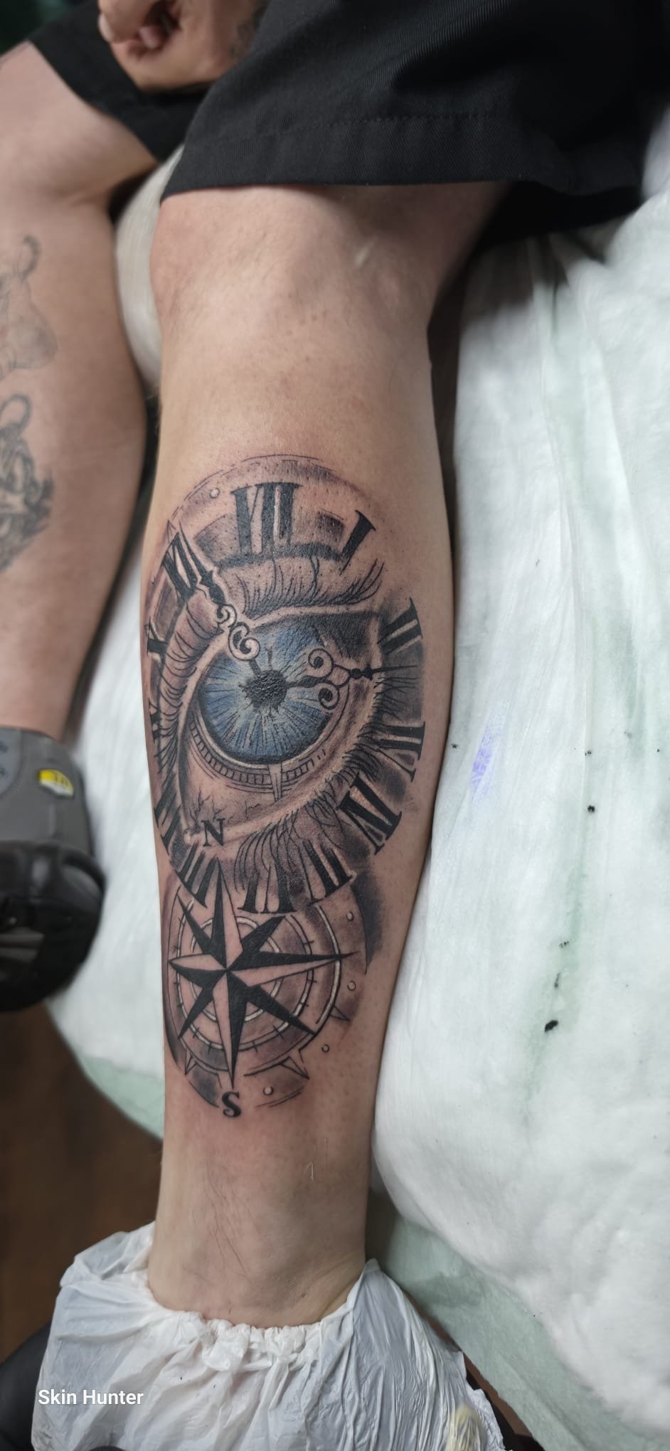 Realistic-Tattoo mit Auge, Uhr und Kompass an der Wade in Schwarz-Grau