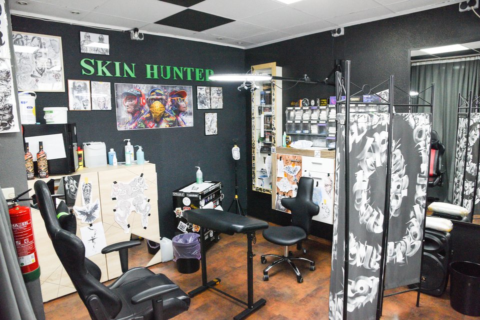 Arbeitsplatz im Studio vor der schwarzen Wand mit grünem Skin-Hunter-Schriftzug