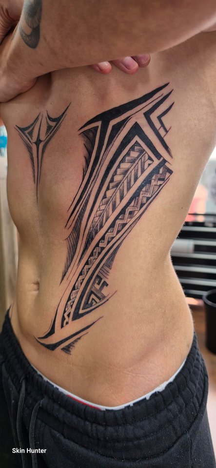 Tribal-Muster in Schwarz an Rippen und Bauch